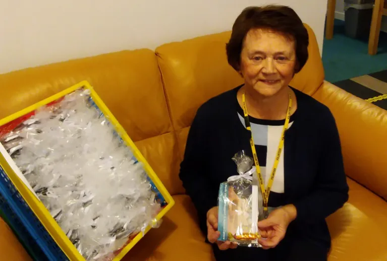 A smiling lady holding a small gift bag